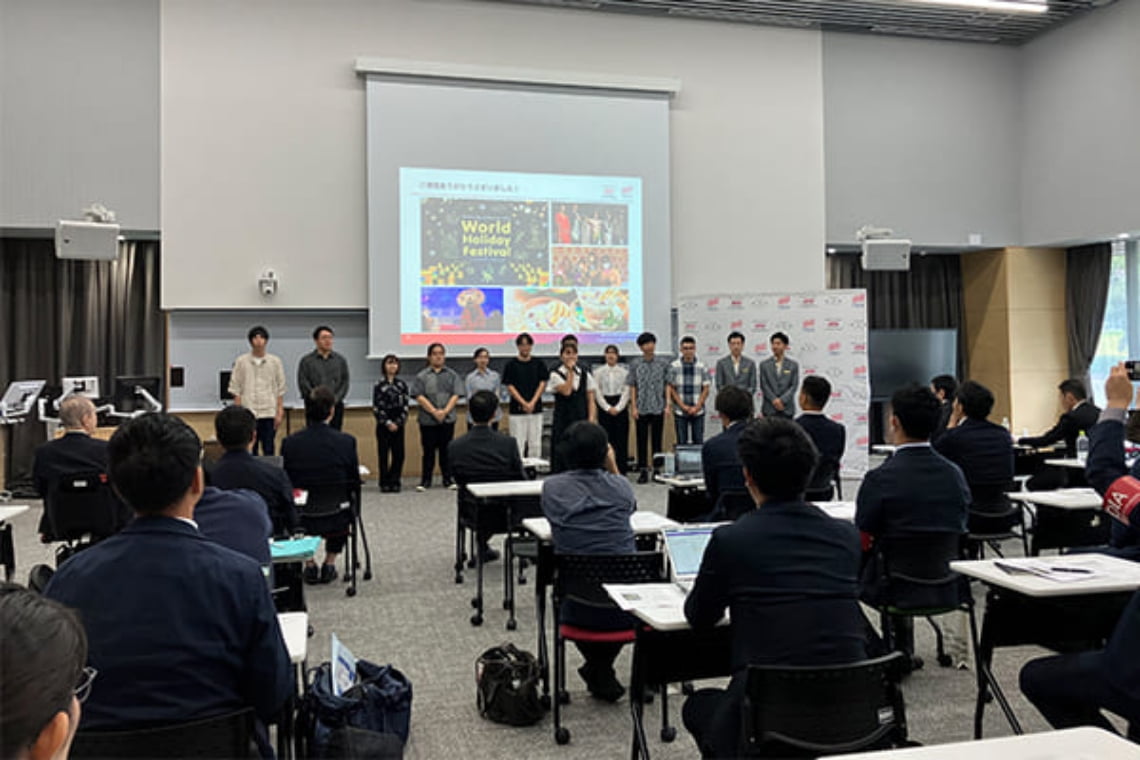 大学と企業が連携した産学連携プログラムの発表会で、学生と関係者が前方でプレゼンテーションを行う様子