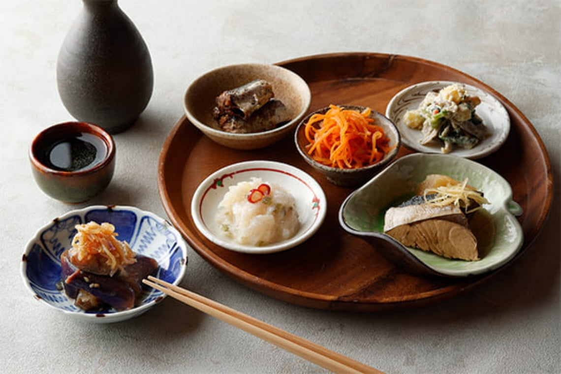 地元食材を使った郷土料理を盛り付けた和定食。小鉢と主菜を木の盆に並べた温かみのある食事風景